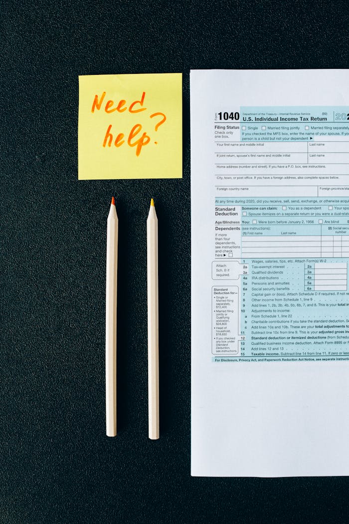 about-01 A tax form 1040 with a 'Need help?' sticky note and pencils on a black surface.